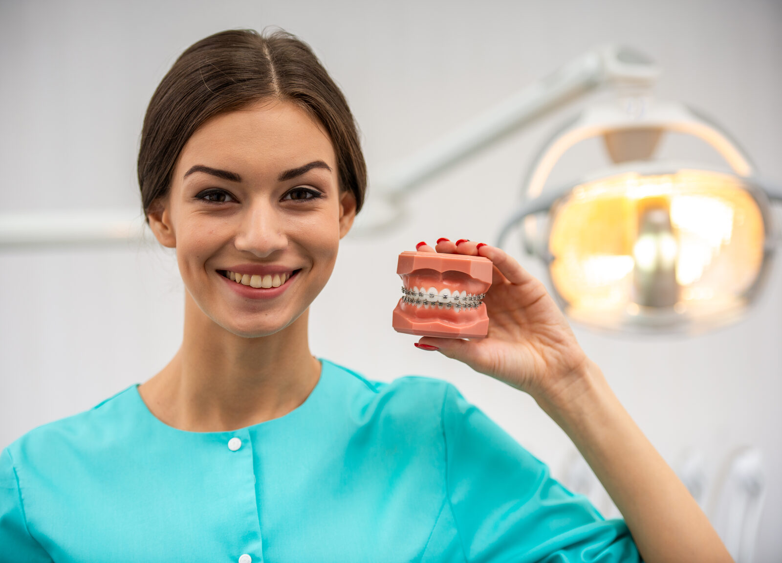 Louisville orthodontist holding a clear-aligner and braces dental model