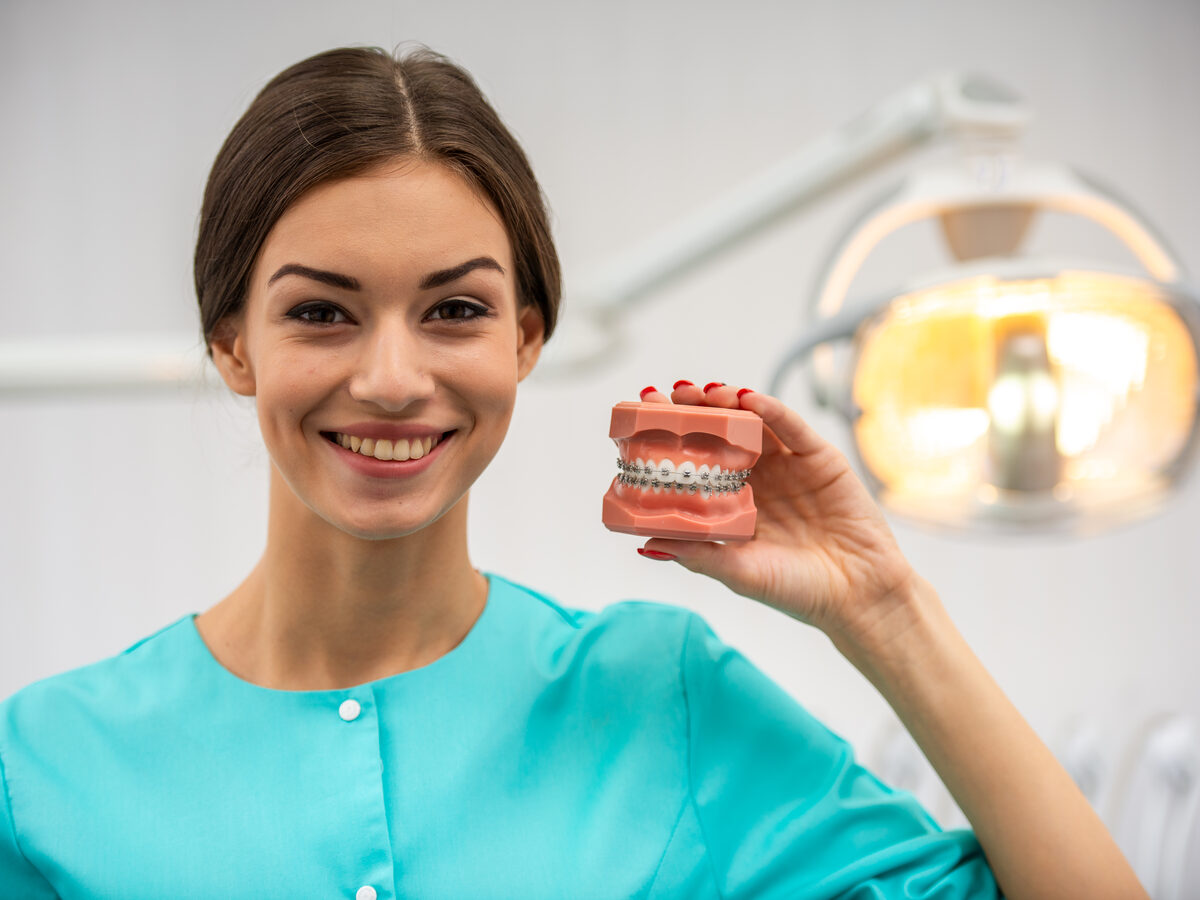 Smiling woman holding a dental model with braces