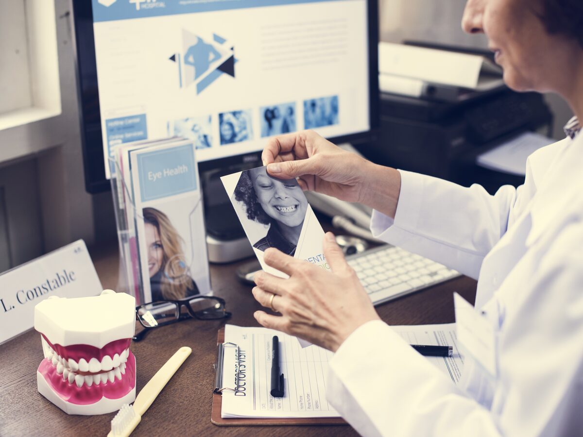 Dentist reviewing a young patient photo at a desk with a dental model