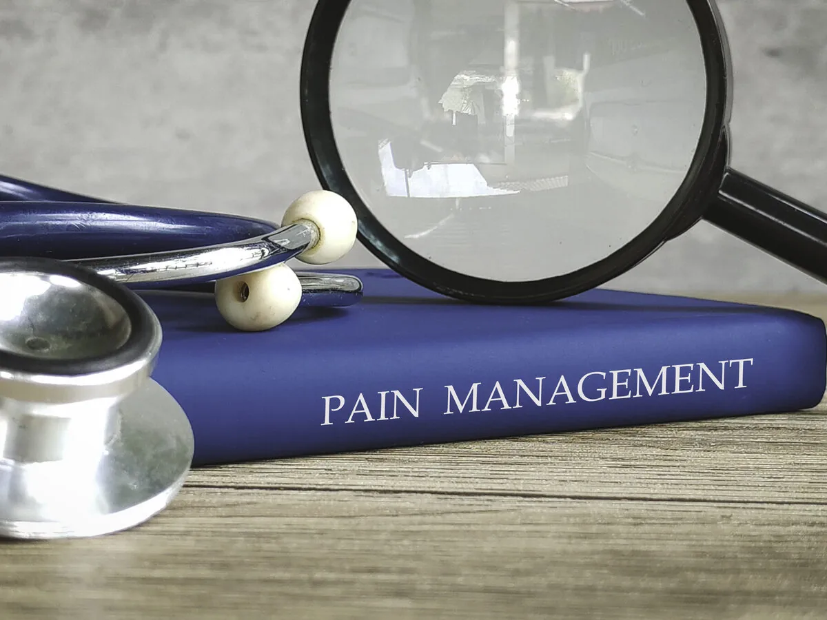 Pain management reference book with a stethoscope on a desk