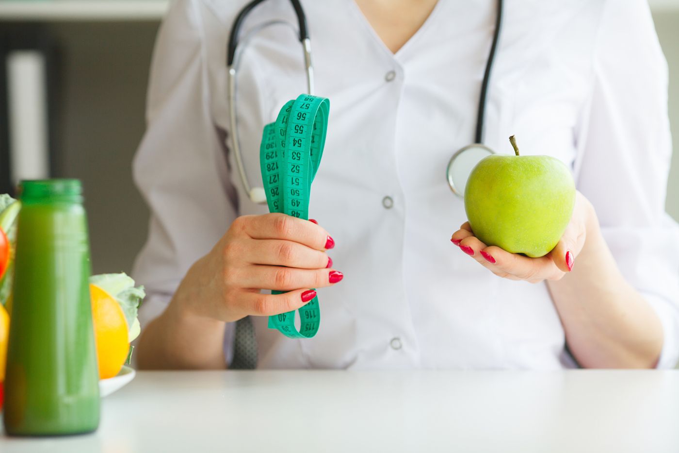 Nutritionist holding an apple with a tape measure during a wellness consultation