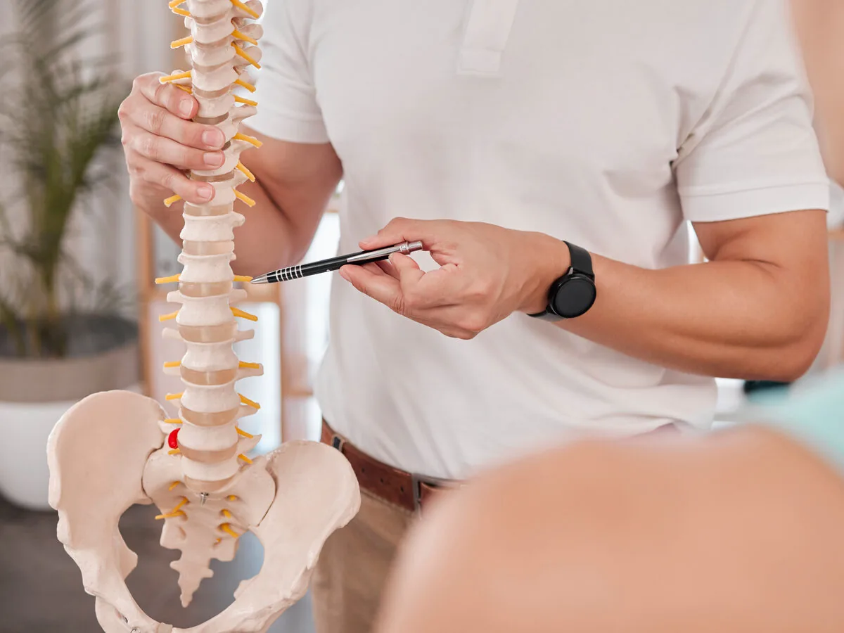 Doctor explaining a spine model to a patient — orthopedic and interventional pain practice marketing